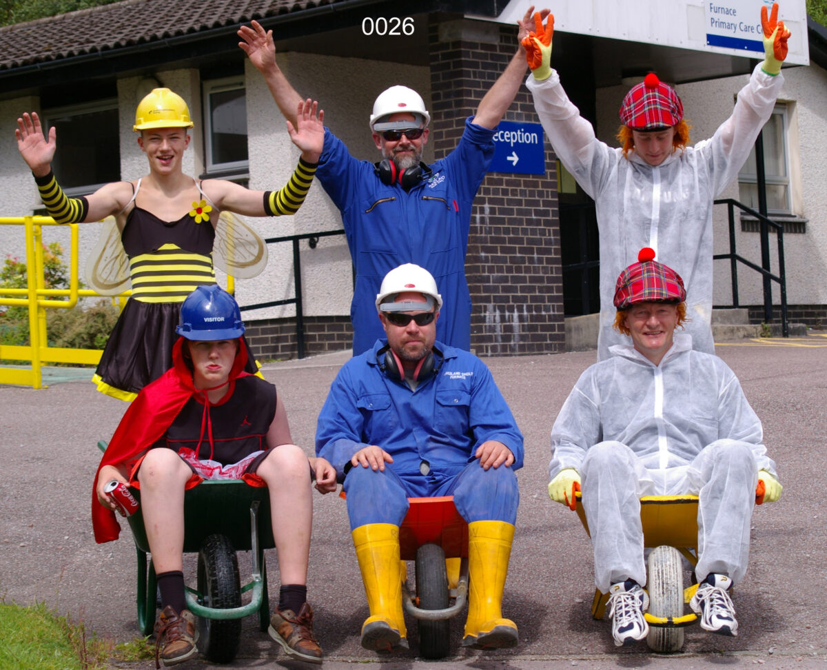 Six people in fancy dress with wheelbarrows